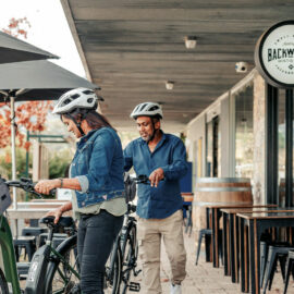 Couple riding their bikes and stopping at Backwoods Distilling Co. for a gin and whiskey tasting on the Beechworth to Yackandandah Rail Trail