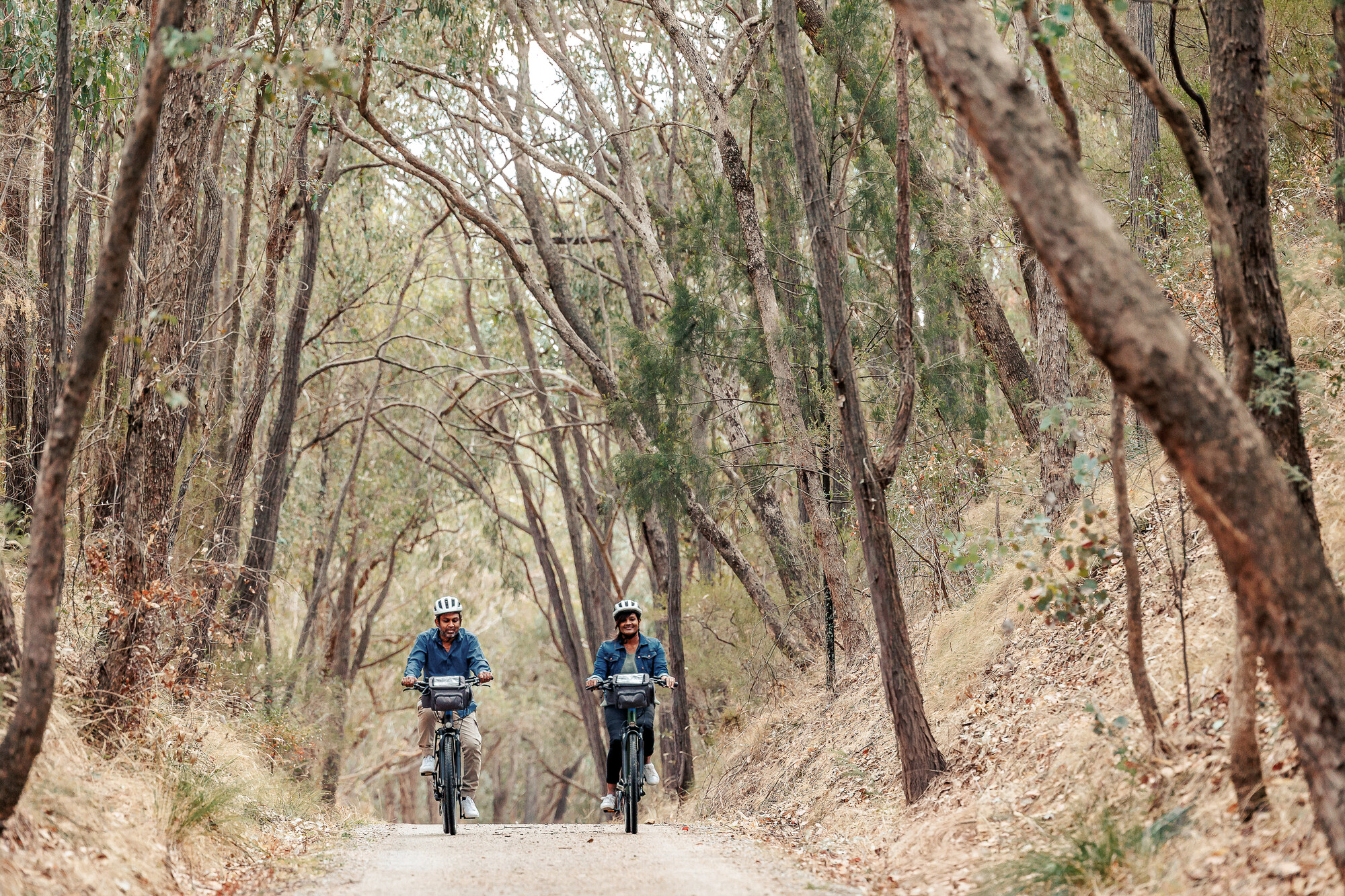 Couple cycling through a historic railway cutting on the Beechworth to Yackandandah Rail Trail.