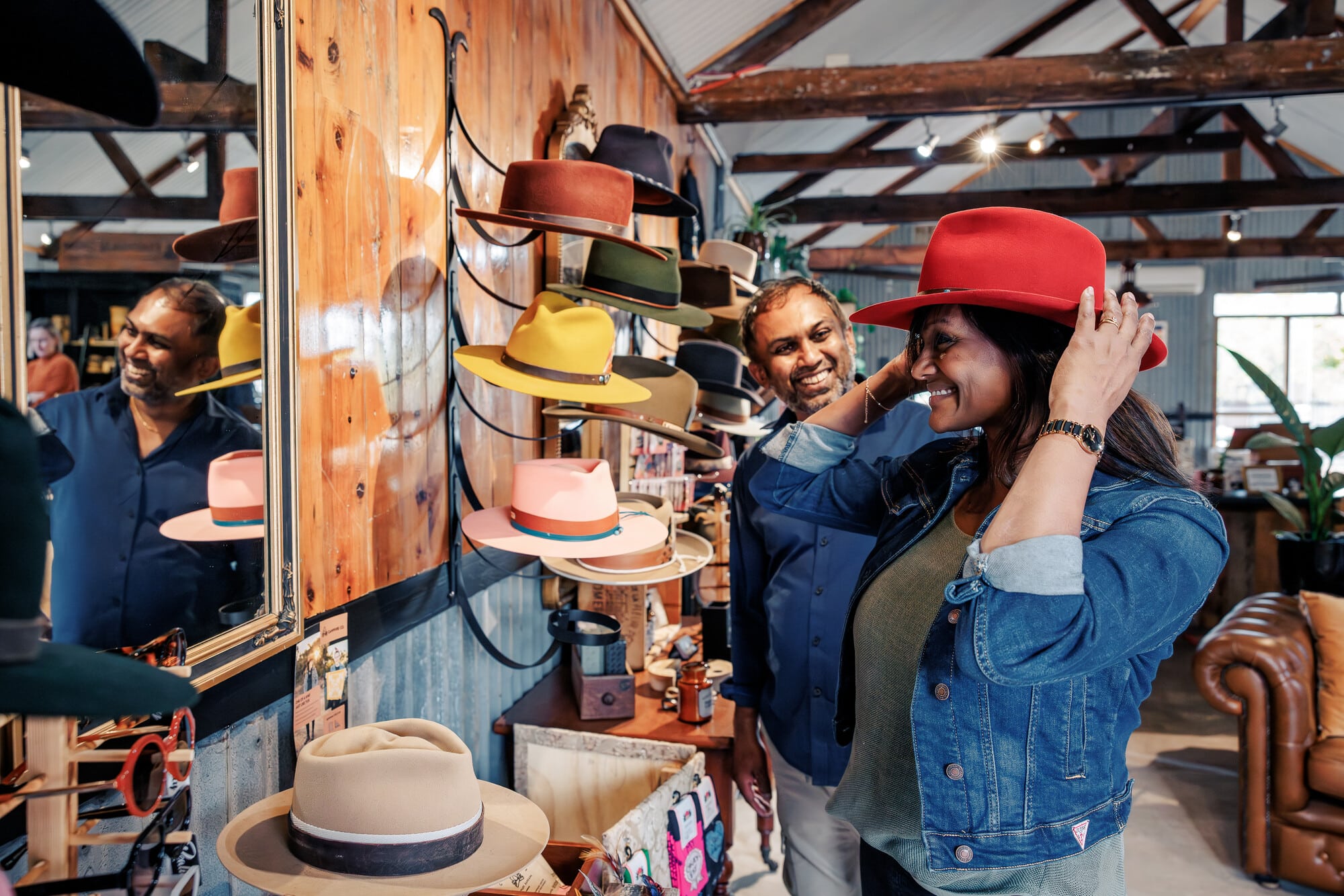 Couple trying on hats at Feather & Drum Co on their Beechworth to Yackandandah Rail Trail cycling adventure